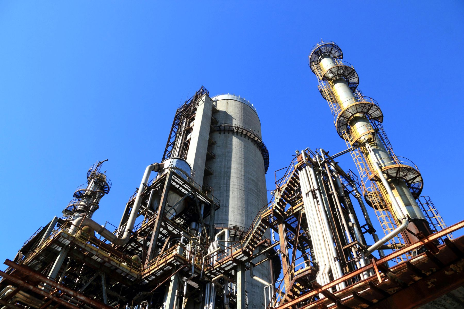 Petrochemical refinery distillation columns and flare stacks against blue sky