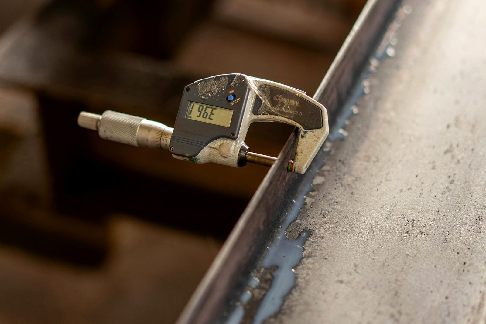 Precision digital micrometer measuring steel plate dimensions to API standards
